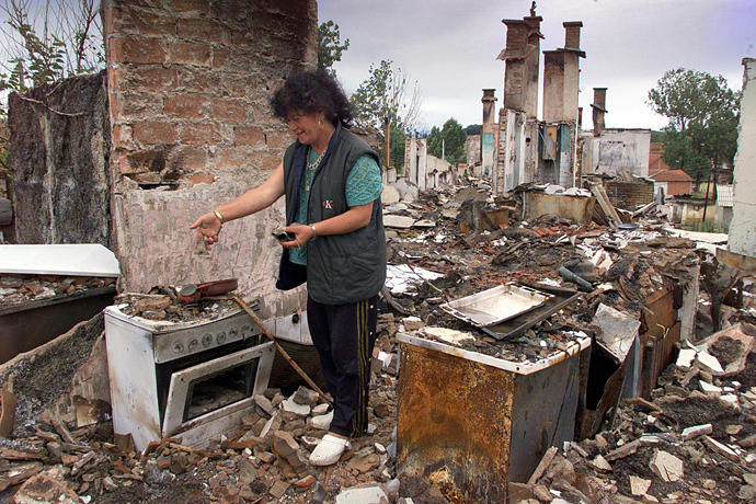 An Ethnic Albanian refugee from Kosovo looks at her destroyed kitchen after she returned to her house, 22 June 1999 on a road near Orahovac (AFP Photo)